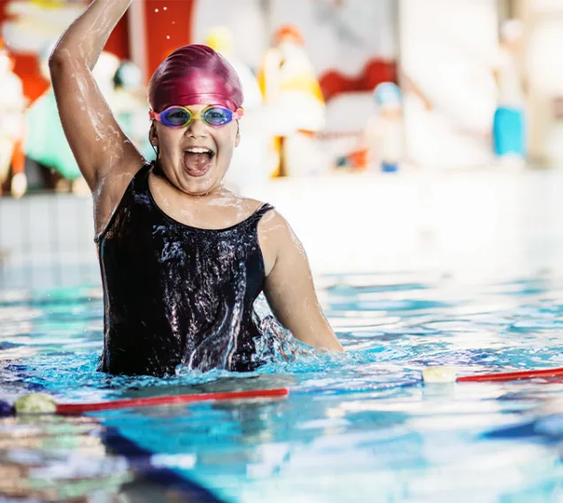 A young girl jumping out of a pool swim lane