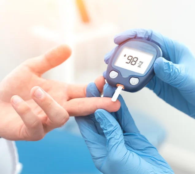 Image of a doctor's hand holding a patients hand, taking their blood sugar
