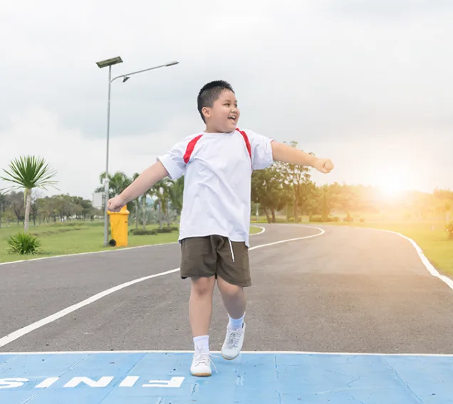 a young boy running over a finish lines with his arms in the air smiling
