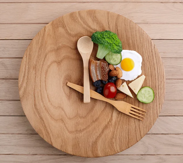 image of a plate with a spoon and fork surrounding a group of cheeses, veggies and nuts