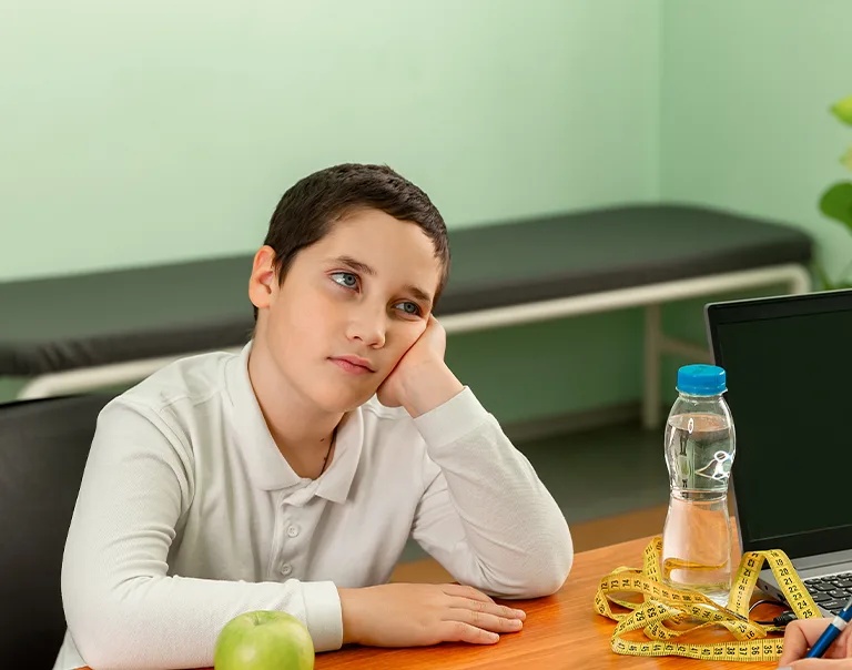 image of a child sitting across from a doctor at a desk with his chin in his hands