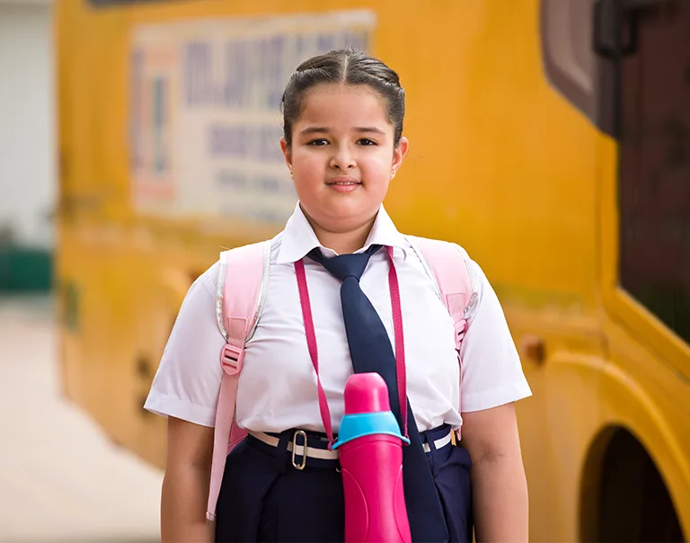 image of a young girl standing in front of a school bus