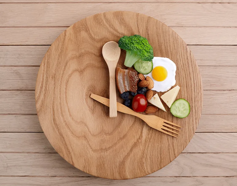 image of a plate with a spoon and fork surrounding a group of cheeses, veggies and nuts