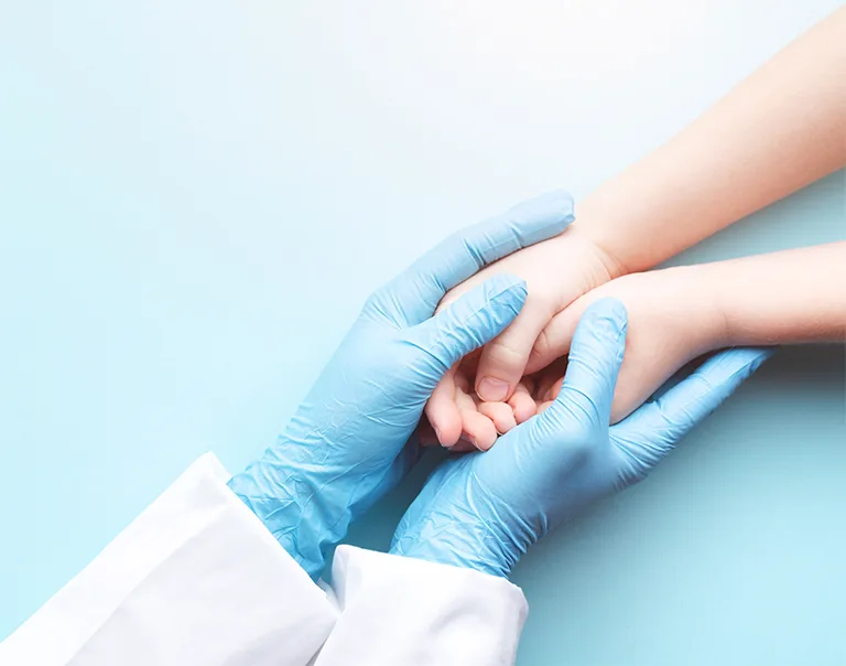 image of a doctor with blue gloves on holding a child hands