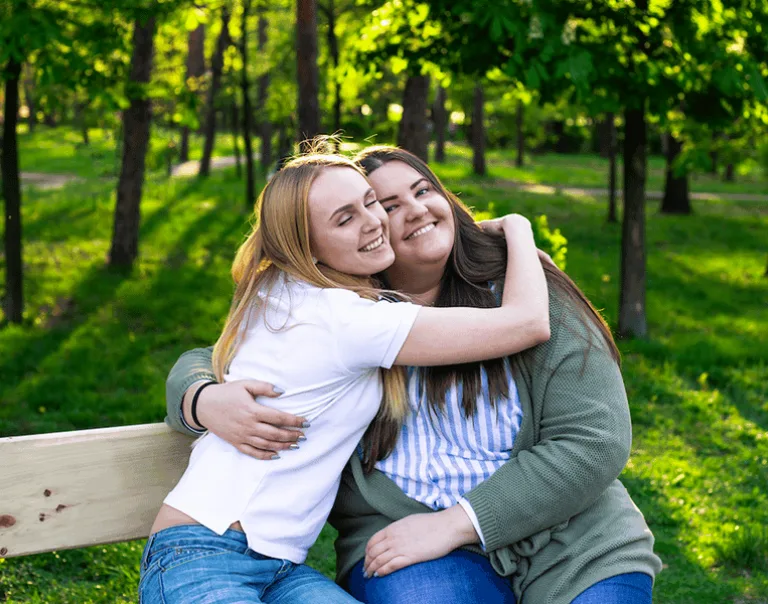 image of two young women smiling and hugging