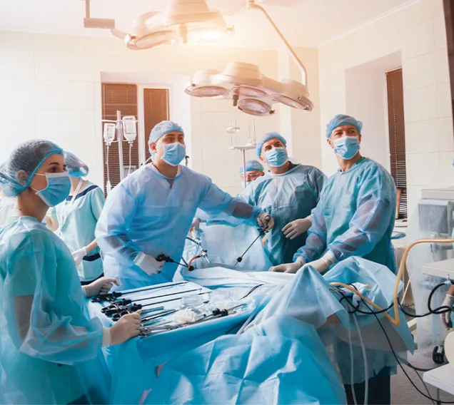 Doctors in surgical masks and gear, standing over an operating table