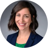 Headshot of Stephanie Smith with short brown hair, wearing a navy blazer with a gray background