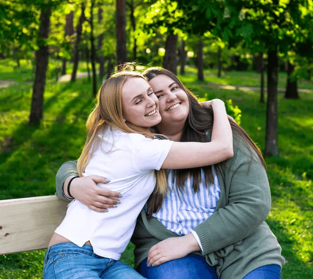 image of two young women smiling and hugging