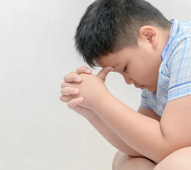 image of a young boy sitting with his forehead in his hands