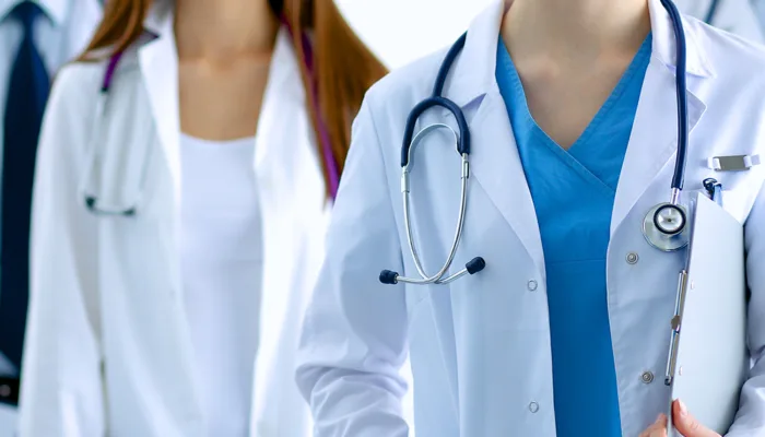 2 people wearing doctors coats with stethoscopes around their necks and holding charts