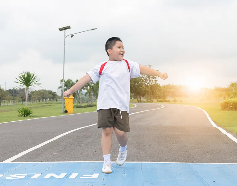a young boy running over a finish lines with his arms in the air smiling