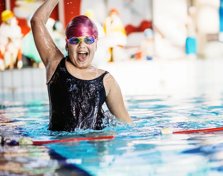 A young girl jumping out of a pool swim lane
