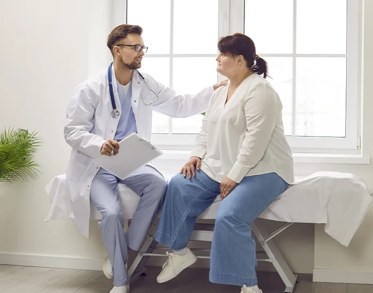 doctor sitting with a patient on a hospital bed comforting her