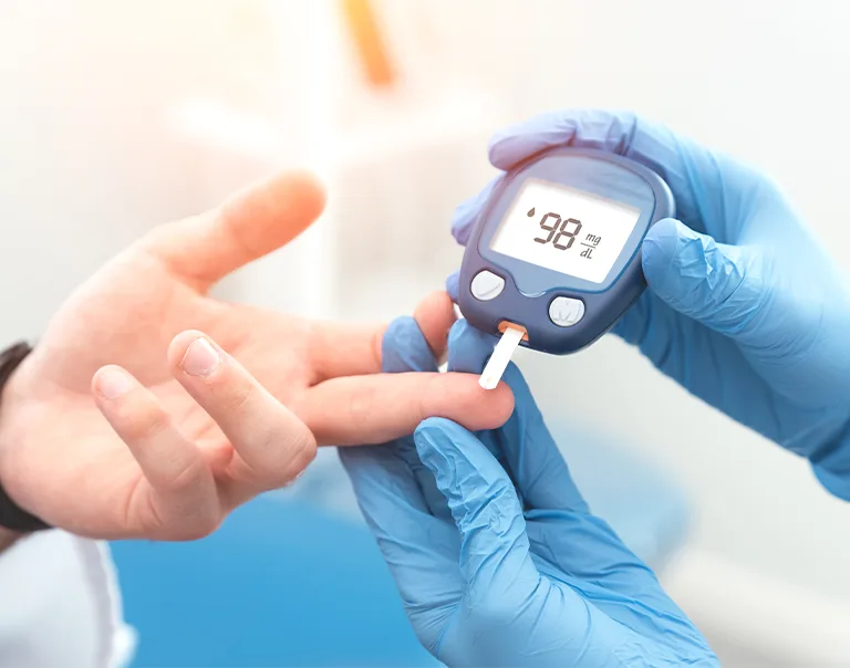Image of a doctor's hand holding a patients hand, taking their blood sugar