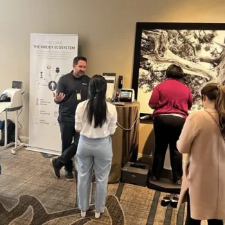 Exhibitor at OMASummit25 engaging with conference attendees.