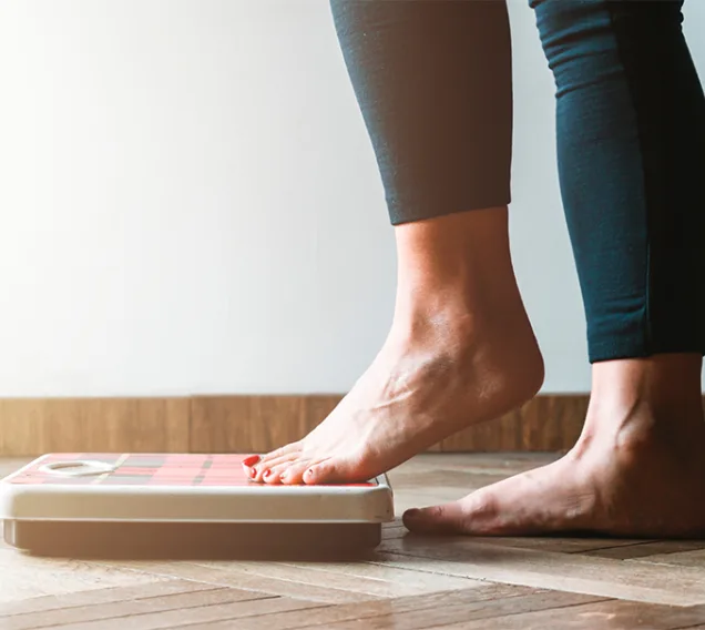 image of a scale on the floor and a woman stepping onto it