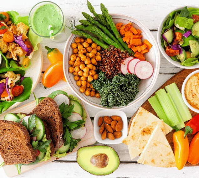 Aerial shot of a white table with a variety of bowls of fruit, vegetables, grains, and carbs