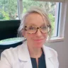 Headshot of Rachel Smith, DNP, FNP-C, CNM, NBC-HWC, sitting in a desk chair wearing a white coat with a blue shirt