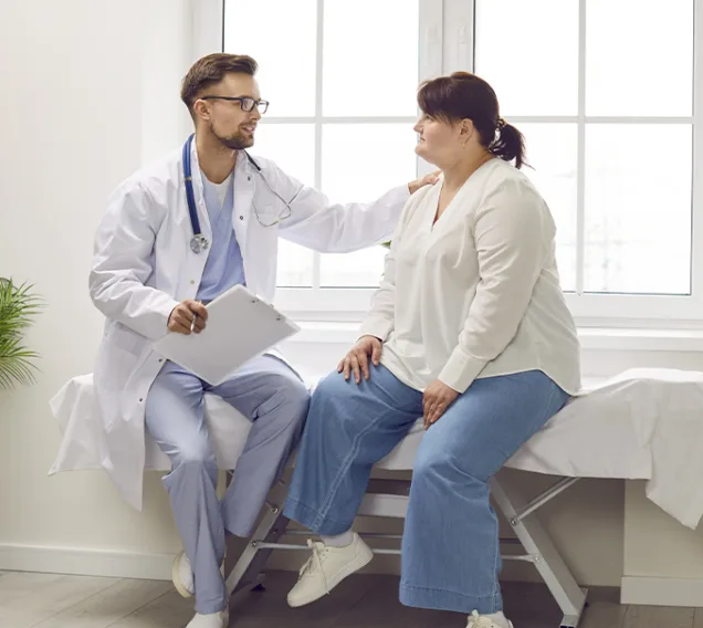doctor sitting with a patient on a hospital bed comforting her