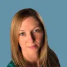 Headshot of Kimberley Sampson, MD, FACOG, DABOM, in front of a blue background with a green shirt