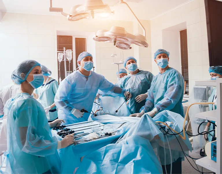Doctors in surgical masks and gear, standing over an operating table